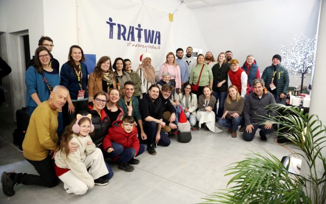 grupa dorosłych i dzieci przed napisem Tratwa